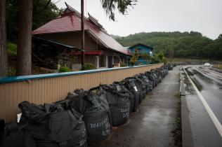 Säcke mit radioaktiv kontaminierter Erde, Schlamm und Gras lagern direkt vor den Haustüren der Menschen in Tamura, 2013
