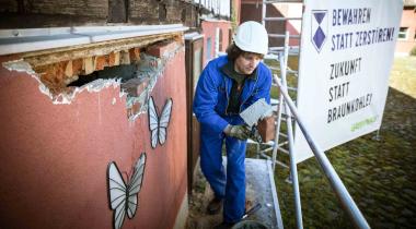 Pödelwitz: Greenpeace-Aktivist mauert Loch in leerstehendem Gebäude zu, um es vor Verfall zu schützen.