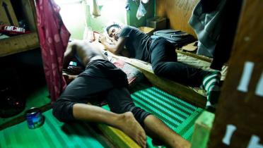 Zwei Fischer liegen dicht aneinander gedrängt in ihrem engen Schlafraum. 