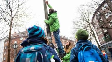 Greenpeace-Mitarbeiter bringt Messvorrichtung an. Damit wird der Stickoxidgehalt der Luft nahe einer Berliner Schule gemessen.