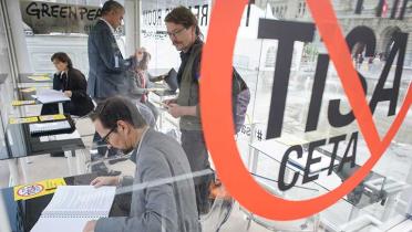 Gläserner Leseraum vor dem UNO-Hauptgebäude in Genf. Mehrere Menschen lesen TiSA-Verhandlungstexte.