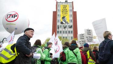 Stop-TTIP-Demo in Hannover. Im Hintergrund hängen Kletterer ein riesiges Banner mit der Aufschrift "Yes we can stop TTIP" an ein Haus.