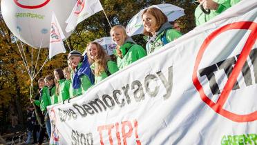 Greenpeace-Aktivisten nehmen im Jahr 2015 an der großen bundesweiten Demonstration gegen TTIP in Berlin teil. Sie tragen Schirme, Ballons und Banner mit dem Protest "Save Democracy - Stop TTIP!".