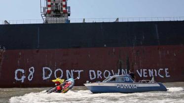 Aktivisten malen „G8, lasst Venedig nicht untergehen“ an die Wand eines Kohleschiffes, Juli 2009