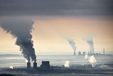 Das Braunkohlerevier in der Lausitz aus der Vogelperspektive, und umgeben von Qualm, der aus den Schornsteinen der Braunkohlekraftwerke kommt. 