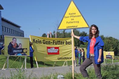 Aktive protestieren mit Banner vor der Firmenzentrale  der Molkerei Müller