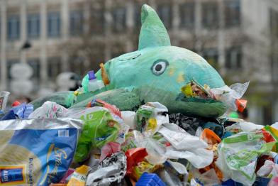 Kinder informieren die Öffentlichkeit über die Verschmutzung der Ozeane mit Plastikmüll. Sie stehen neben einem großen Haufen Plastik.