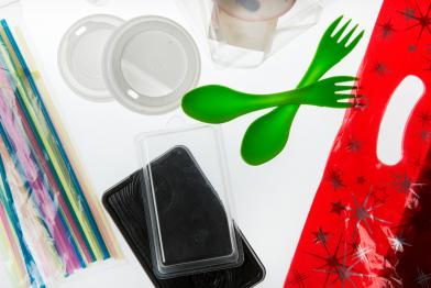 Produktfoto von verschiedenen Kunststoffartikeln, darunter Gabeln, Löffel, Flaschen und Verschlüsse, Verpackungen und Strohhalme aus Kunststoff.