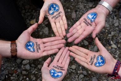 Offene Handflächen mit „Plan Earth First“ Tattoo die nach oben zeigen