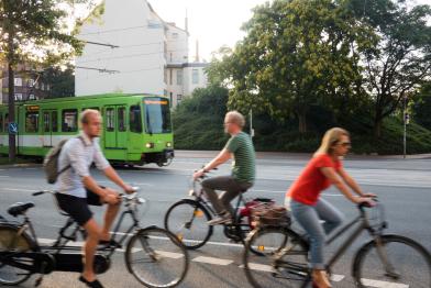 Ein Straßenbahn fährt an Radfahrerinnen und Radfahrern vorbei