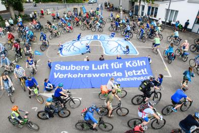Fahrradfahrerinnen protestieren mit einem großen Banner in Form einer Lunge und den Aufschriften "Saubere Luft für Köln" und "Verkehrswende jetzt!" für eine andere Verkehrspolitik
