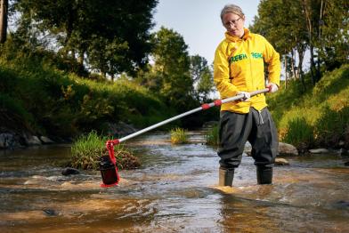 Greenpeace-Mitarbeiter nimmt Wasserproben aus einem Fluss