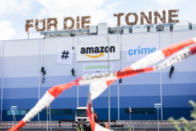 Greenpeace-Aktivist:innen demonstrieren am Amazon Prime Day im Logistikzentrum Winsen an der Luhe gegen die Vernichtung von Neuware. Die Aktivist:innen bringen einen 27 Meter langen Schriftzug aus Versandkartons an, der die Worte "für die Mülltonne" bildet. Das Logo des Online-Versandhändlers veränderten sie mit Bannern zum Hashtag "#amazoncrime".