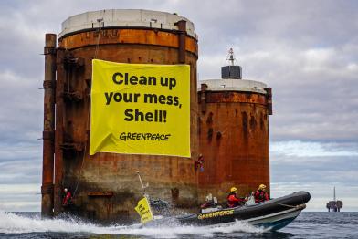 Kletterer:innen erklimmen Ölplatformen  und hängen Banner mit der Aufschrift "Shell, räumt euren Dreck weg" und "Stoppt die Meeresverschmutzung" auf.