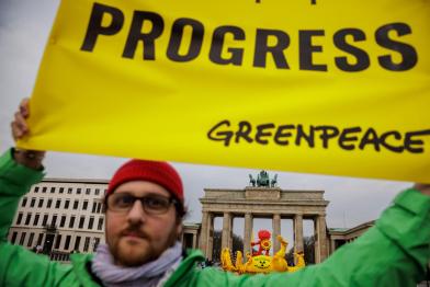 Ein Greenpeace Aktivist hält ein Banner "Progress" vor dem Brandenburger Tor hoch. Er feiert die Abschaltung von Isar II, Emsland und Neckarwestheim II, die letzten drei deutschen Atomkraftwerke, am 15. April 2023.