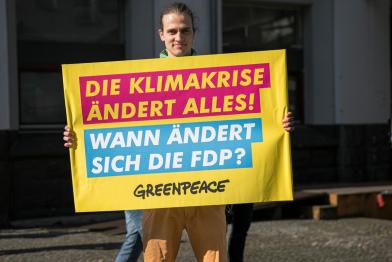 Mann mit Protestplakat "Die Klimakrise ändert alles, wann ändert sich die FDP?"