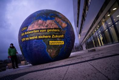 Protest  auf CDU-Parteitag. Aktivist:innen stehenneben einem fünf Meter hohen Ballon in Form einer Weltkugel mit Aufschrift: "CDU: Mit Antworten von gestern gibt es keine sichere Zukunft."