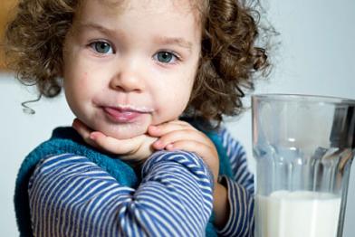 Mädchen, 2 Jahre, trinkt Milch aus einem Glas. 