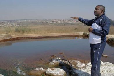 Matthews Hlabane zeigt, wie die sauren Grubenwässer in den Tümpel gelangen. Februar 2008