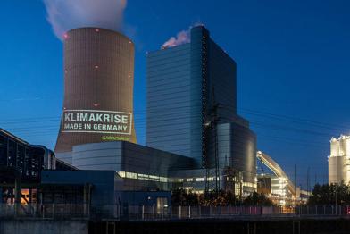 Greenpeace-Aktivistinnen und -Aktivisten projizieren auf den 180 Meter hohen Kühlturm des Kraftwerks Datteln 4 „Klimakrise – Made in Germany“.