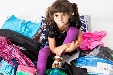 Kind sitzt auf einem Haufen Kleidung