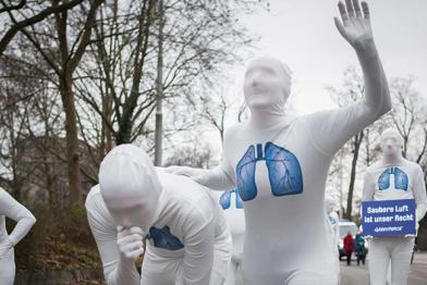 Performance auf Deutschlands schmutzigster Straße, dem Neckartor in Stuttgart: In weißen Ganzkörperanzügen stellen Aktivisten symbolisch auf zwei der sechs Fahrspuren eine Gruppe Atemwegserkrankter dar, die vor schmutziger Stadtluft flieht.