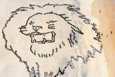 Am Strand von Durban formatieren Jugendliche sich gemeinsam zu einem Löwenhaupt, Dezember 2011