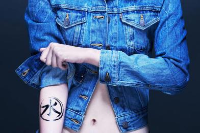 Eine Frau krempelt den Ärmel ihrer Jeansjacke hoch, darunter kommt das Detox-Logo zum Vorschein. 