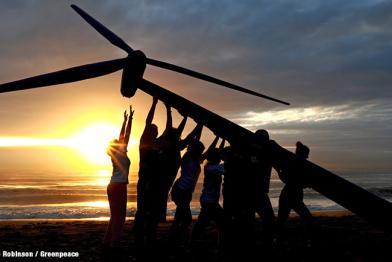 Menschen stellen eine Windturbine auf.