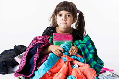 Mädchen in einem Haufen Kleidungsstücke