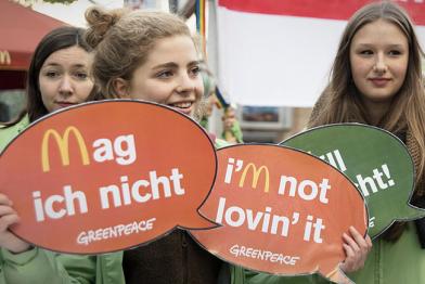 Junge Aktivistinnen protestieren mit Sprechblasen gegen McDonald's