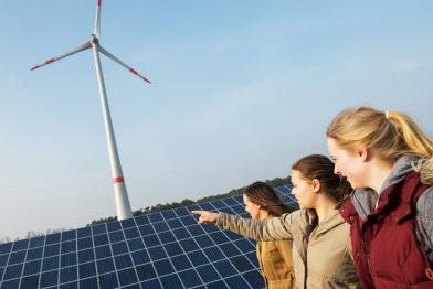 Drei junge Frauen vor Windrad und Solar-Panels in der Energie-Kommune Saerbeck