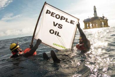 Zwei Schwimmer im Pazifik protestieren mit einem Banner vor der Polar Pioneer