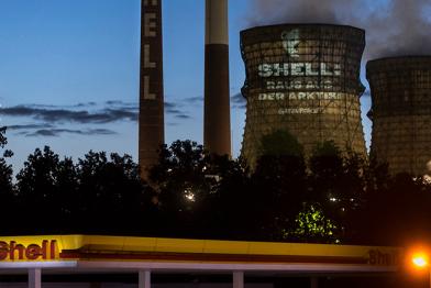 Greenpeace-Projektion hinter Shell-Tankstelle