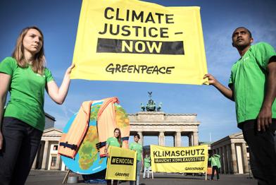 Aktivisten in Berlin vorm Brandenburger Tor, sie zeigen einen Globus mit angelegter Rettungsweste