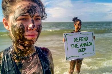 Ölbeschmutzte Aktivisten in Brasilien mit Banner