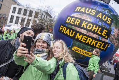 Greenpeace-Aktivisten machen ein Selfie vor Merkel-Skulptur