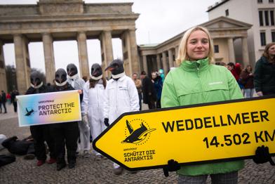Greenpeace-Aktivistin mit Wegweiser vorm Brandenburger Tor