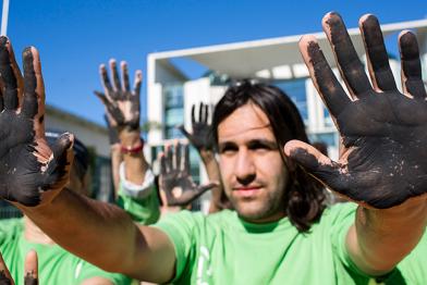 Greenpeace-Aktivisten mit schwarzen Händen demonstrieren vorm Bundeskanzleramt für den Kohleausstieg