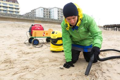 Greenpeace-Aktivist mit Staubsauger am Strand von Borkum