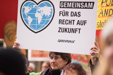 Demonstrant mit Schild "Gemeinsam für das Recht auf Zukunft"
