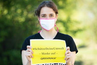 Greenpeade-Mitarbeiterin mit Stoffmaske
