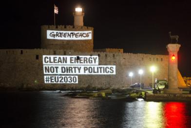 Eine Projektion mit dem Text "Clean Energy not dirty politics" ist bei Nacht an die Mauern der Burg Rhodos projiziert