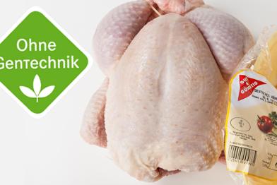 Ein rohes Hühnchen neben einer ausgerissenen Packung von Gut und Günstig neben dem Siegen "Ohne Gentechnik"