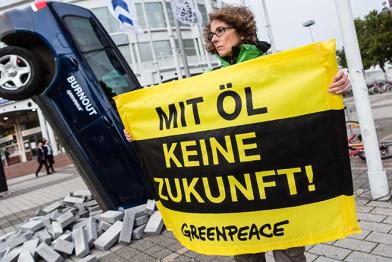 Mit einem schräg im Boden steckenden VW-Auto mit qualmendem Auspuff demonstrieren Greenpeace-Aktivisten vor der Internationalen Automobilausstellung (IAA) in Frankfurt gegen die Modellpolitik der Autoindustrie.