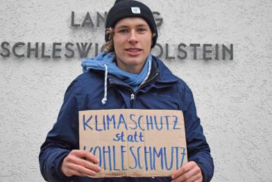 Jakob Blasel mit Schild "Klimaschutz statt Kohleschmutz" vor Landtag in Kiel
