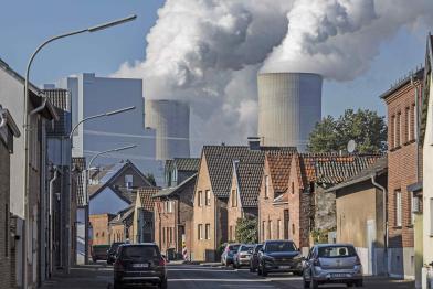 Dampfschwaden des Kraftwerks Neurath über Häusern
