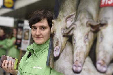 Aktivisten halten ein Plakat - es zeigt dreckige, eng stehende Schweine