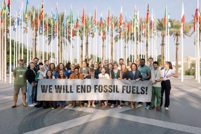 Greenpeace-Delegation bei der COP28 mit Banner "we will end fossil fuels"