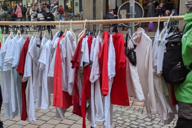 Eine Stange mit weißen und roten Shirts die das Konsumverhalten widerspiegeln